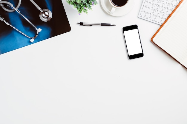 Medical workplace with stethoscope,notebook,pen,keyboard,coffee,smart phone and x-ray film