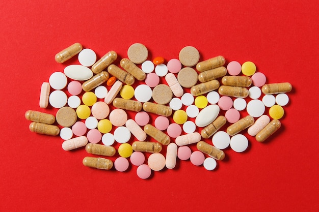 Medication white colorful round tablets arranged abstract on red color background