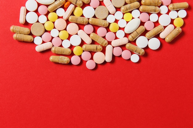 Medication white colorful round tablets arranged abstract on red color background