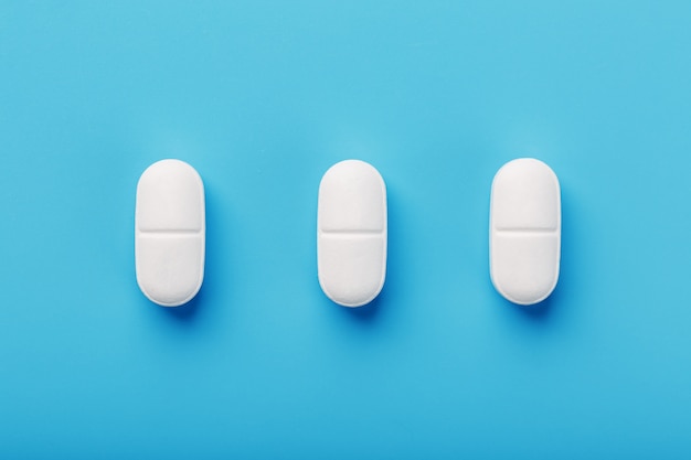 Medicinal tablets in a row on blue