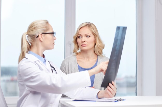 medicine, age, health care and people concept - woman patient and doctor with spine x-ray scan meeting in medical office