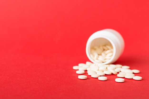 Medicine bottle and white pills spilled on a light background Medicines and prescription pills flat lay background White medical pills and tablets spilling out of a drug bottle