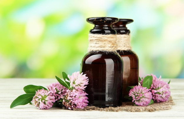 Medicine bottles with clover flowers on wooden table outdoors