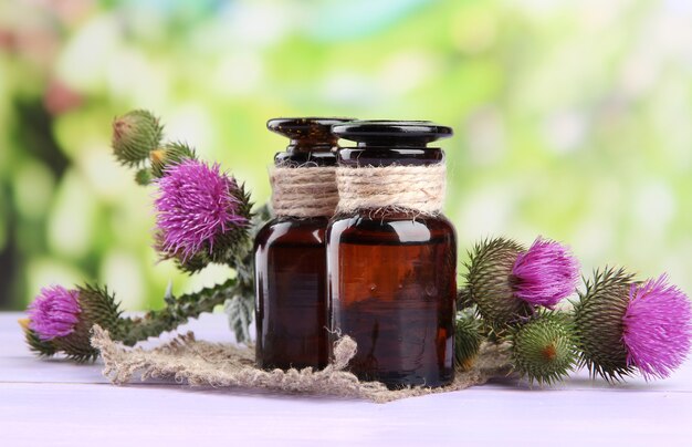 Medicine bottles with thistle flowers on nature surface