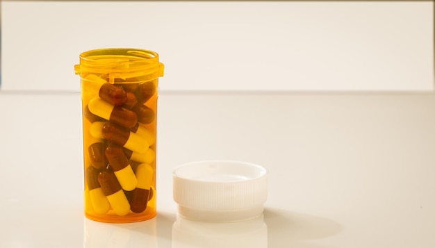 Medicine capsule pill near bottle container on table for medication drug treatment or abuse concept