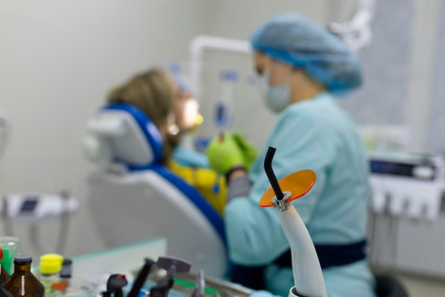 Medicine dentistry and healthcare concept dentist using dental curing UV lamp on teeth of patient