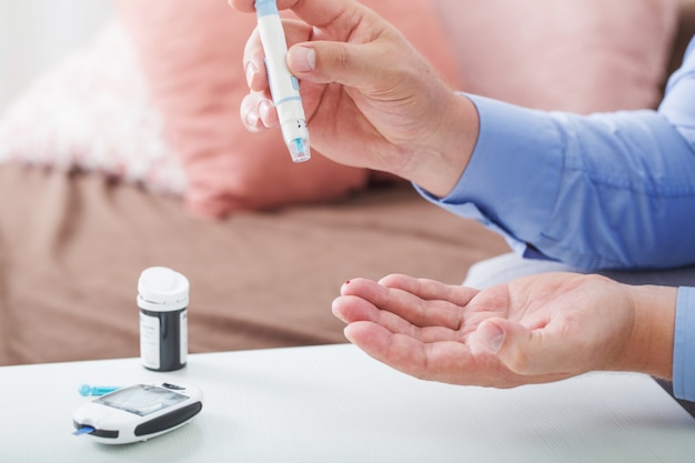 Medicine, diabetes, glycemia, health care and people concept. close up of male finger with test stripe