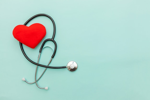 Medicine equipment stethoscope or phonendoscope and red heart isolated on trendy pastel blue background.