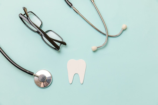 Photo medicine equipment stethoscope white healthy tooth glasses isolated on pastel blue background