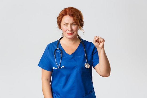 Medicine, healthcare and coronavirus concept. Hopeful and optimistic medical worker showing stay united gesture, clench fist in support, doctor wishing all well, encourage coworkers and team.