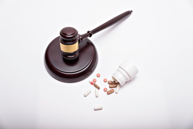 Medicine and law Pills capsules and judge gavel isolated on white background