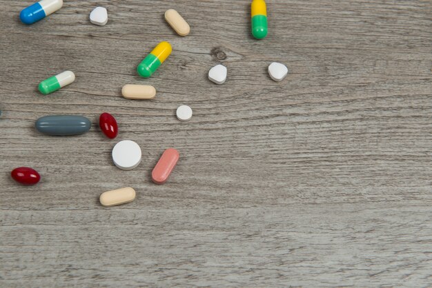 Medicine pills, tablets and capsules on wooden background.