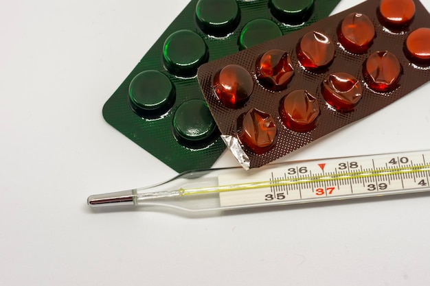 medicine pills and thermometer on white background