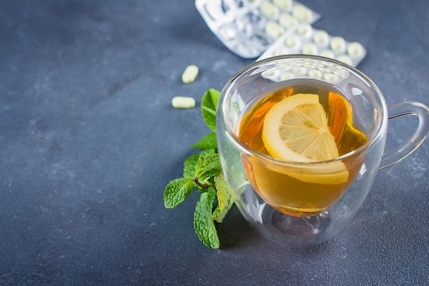 Medicines and Health Healthcare Concept. Cup of hot tea with lemons, pills and thermometer