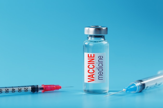 Medicines with syringe Vaccine ampoule on a blue