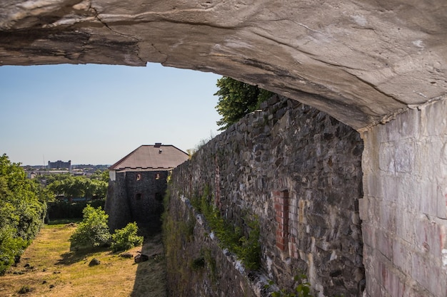 Medieval Gray Castle wall of ancient Uzhgorod castle with a green lawn in front of castle