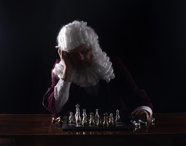 medieval king playing chess, black studio background