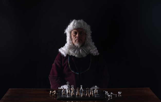 medieval king playing chess, black studio background