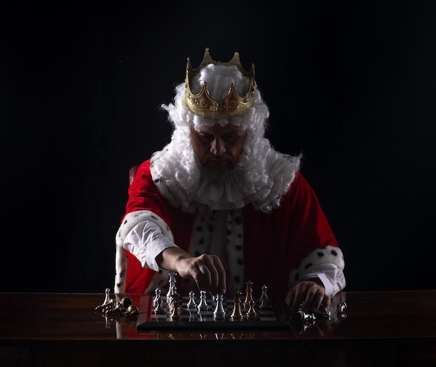 medieval king playing chess, black studio background