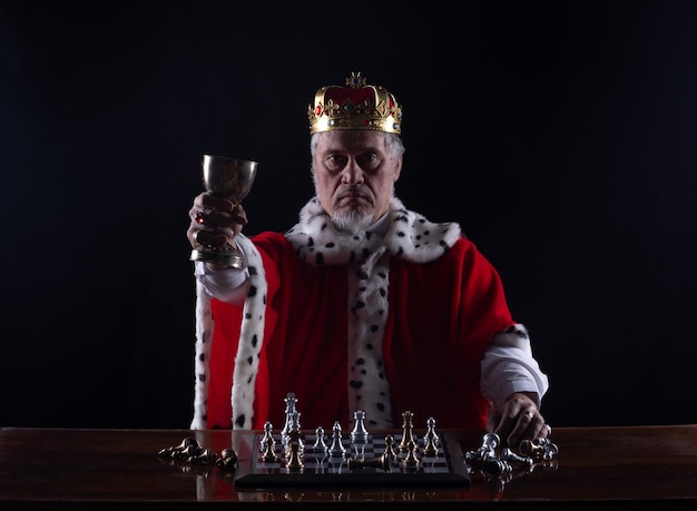 medieval king playing chess, black studio background