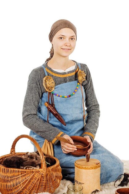 Medieval slavic beautiful woman in historical costume holding utensils for cooking image on white studio background historical concept