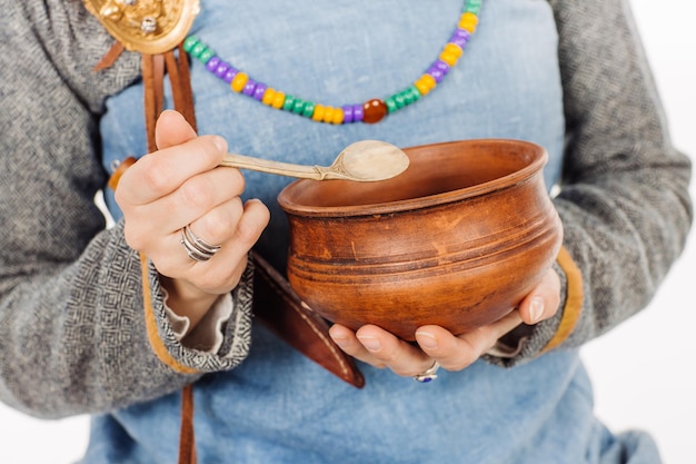 Medieval slavic beautiful woman in historical costume holding utensils for cooking image on white studio background historical concept