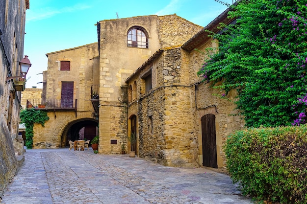 Medieval stone houses with green vines at sunset on a summer day Peratallada Girona Catalonia