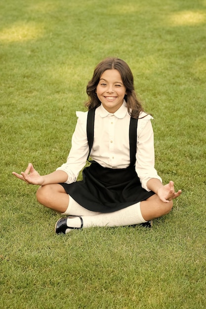 Meditation practice Good vibes Peaceful meditation Learn meditation techniques Girl school pupil sit on lawn Tune in for productive day Yoga training Kid adorable schoolgirl meditate