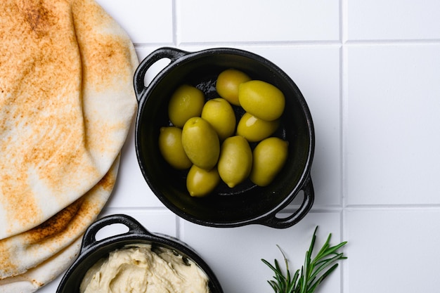 Mediterranean marinated olives set on white ceramic squared tile table background top view flat lay with copy space for text