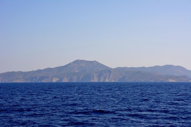 mediterranean sea with dark blue water and waves and coastline with hills on background