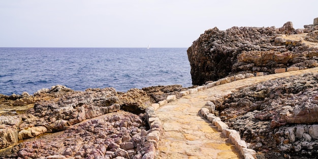 Mediterranean stones pathway in rocks access to beach sea in coast JuanlesPins in Antibes France in web header panoramic