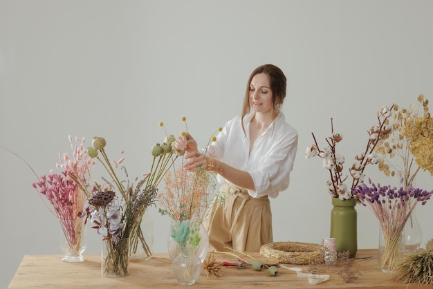 Medium height woman working with dried flowers assemble composition decor and floristry concept