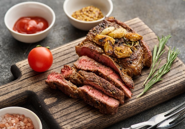 Medium rare Ribeye steak or beef steak on the wooden tray with herbs