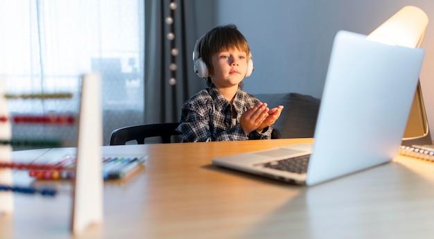 Medium shot of boy having virtual courses on laptop