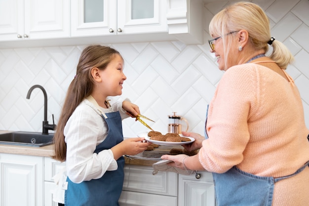 Medium shot grandma and girl with cookies