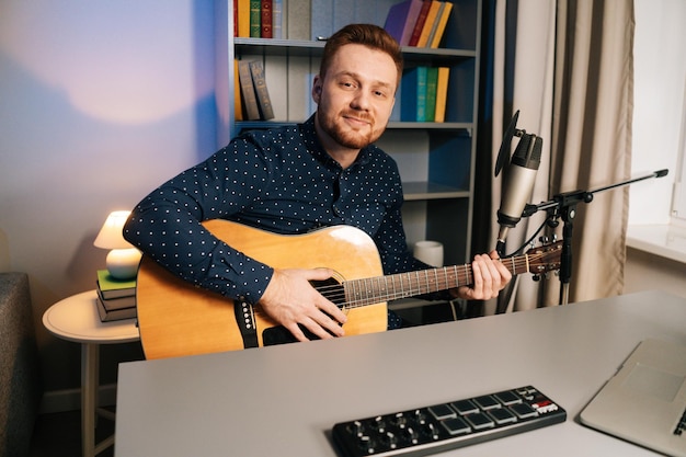 Medium shot of handsome guitarist singer man play on acoustic guitar recording sing song using professional microphone stand at home studio