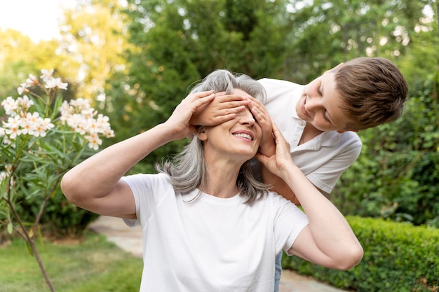 Medium shot kid covering grandmother's eyes