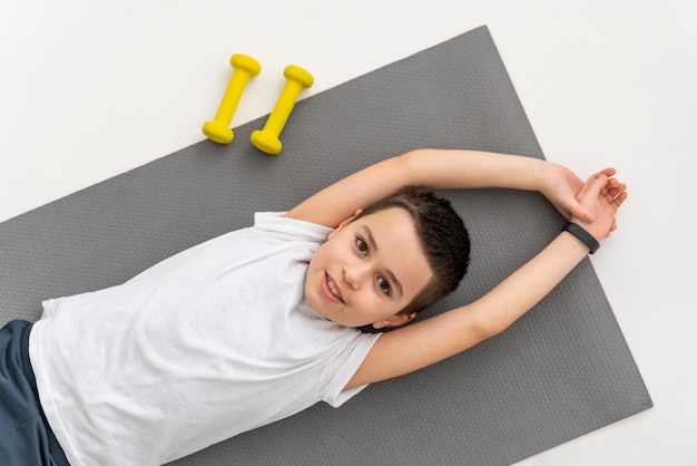 Medium shot kid on yoga mat