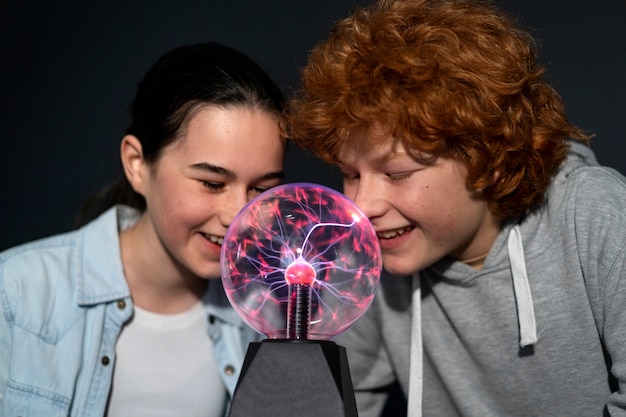 Medium shot kids interacting with a plasma ball