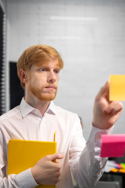 Medium shot man sticking post it on window