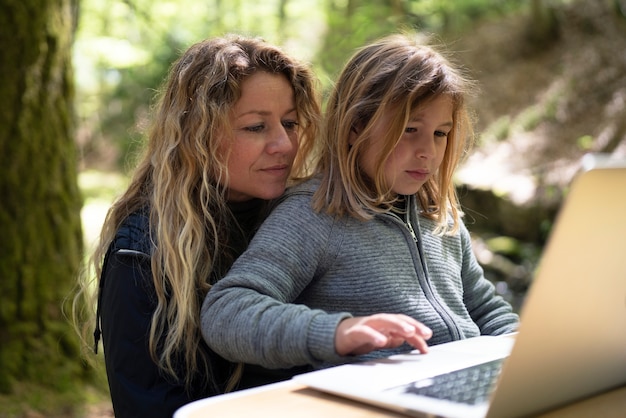 Medium shot mother and girl with laptop