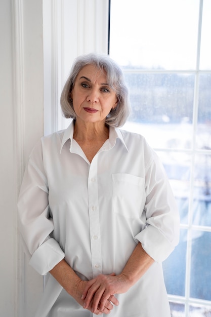 Medium shot old woman near window