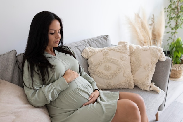 Medium shot pregnant woman on couch