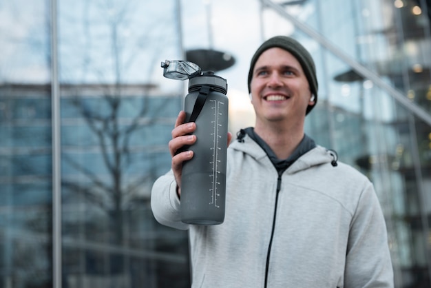 Medium shot smiley man holding water bottle