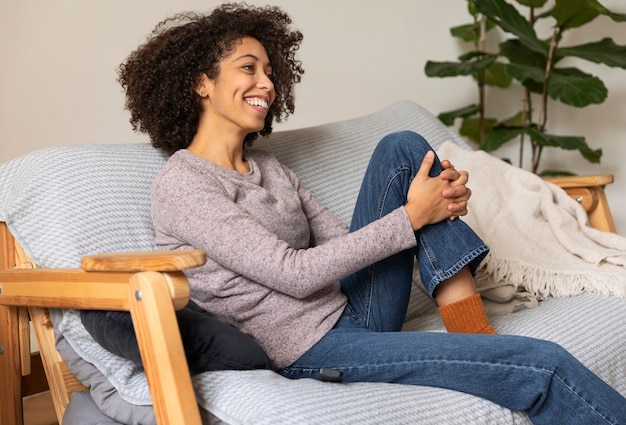 Medium shot smiley woman sitting on couch