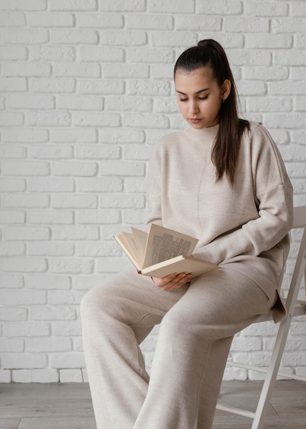 Medium shot woman on chair reading