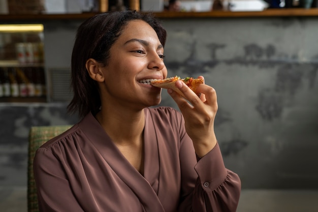 Medium shot woman eating delicious pizza