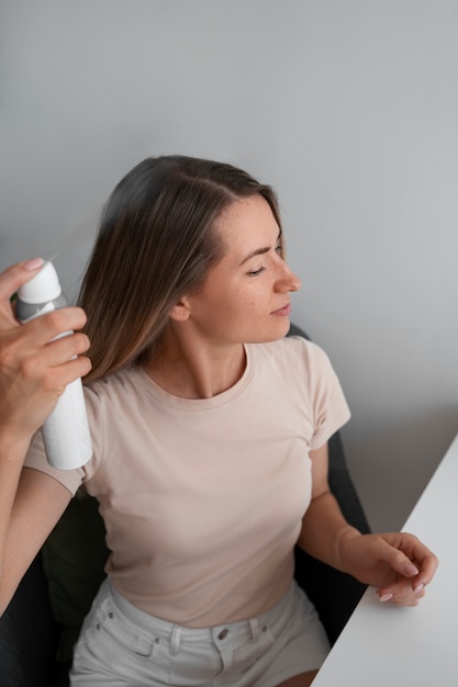 Medium shot woman using dry shampoo at home