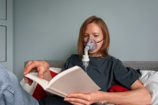 Medium shot woman using nebulizer at home