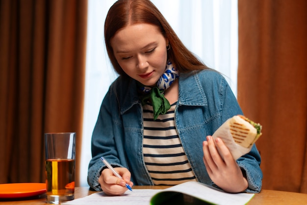 Medium shot woman with  paper-wrapped sandwich